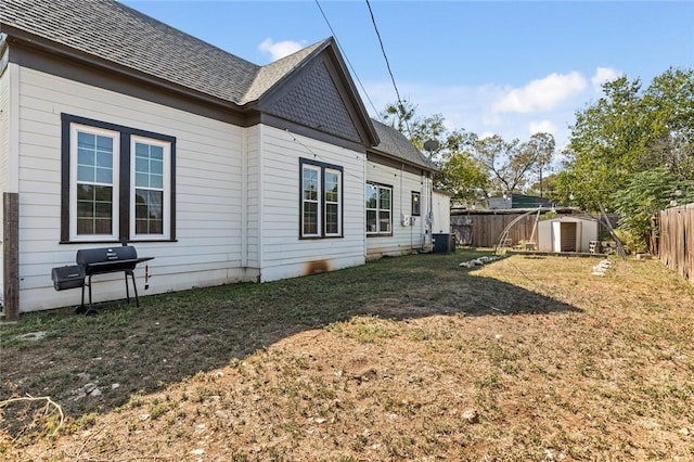 rear view of house with a yard, a shed, and cooling unit