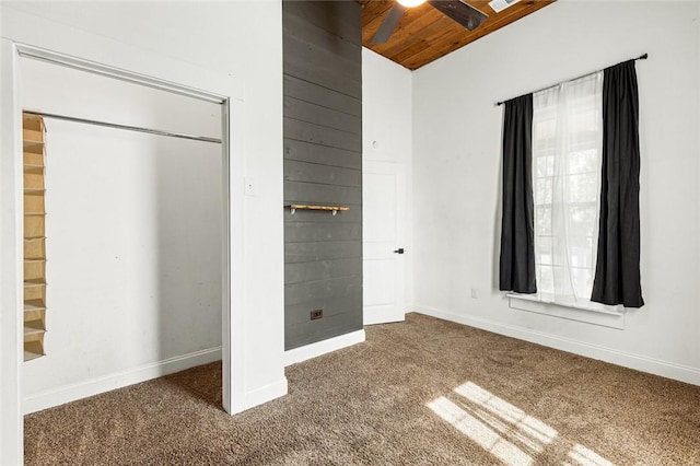 unfurnished bedroom featuring carpet flooring, ceiling fan, a closet, and wooden ceiling