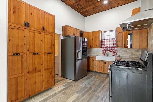 kitchen with backsplash, sink, hardwood / wood-style flooring, island exhaust hood, and stainless steel appliances