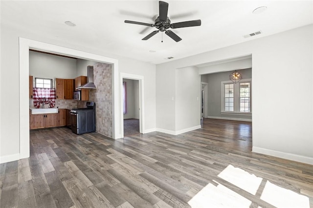 unfurnished living room featuring ceiling fan with notable chandelier, dark hardwood / wood-style floors, plenty of natural light, and sink