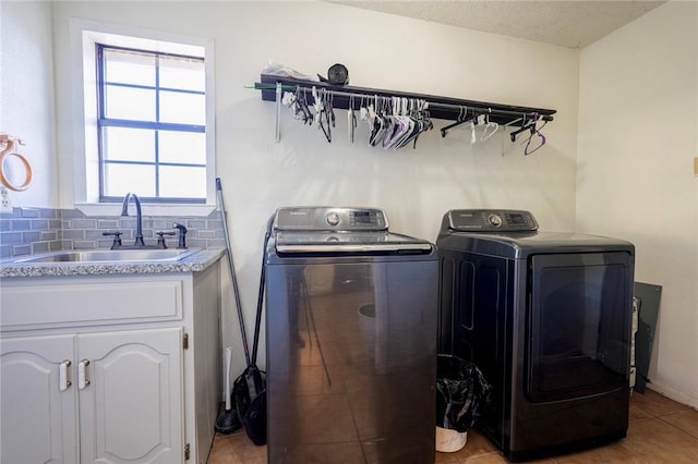 clothes washing area with cabinets, sink, washer and dryer, and a textured ceiling