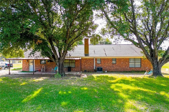 rear view of house featuring cooling unit and a lawn