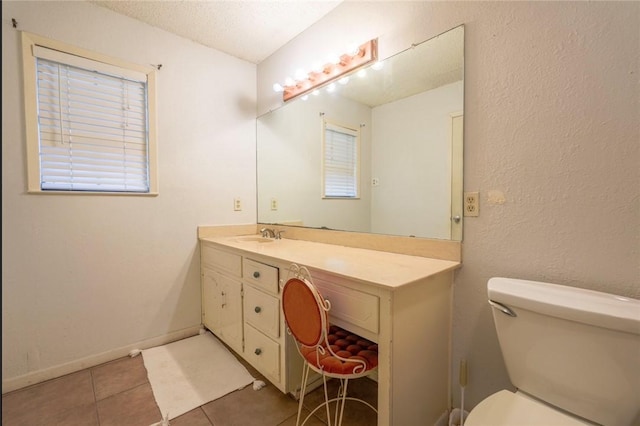 bathroom with toilet, a textured ceiling, vanity, and tile patterned floors