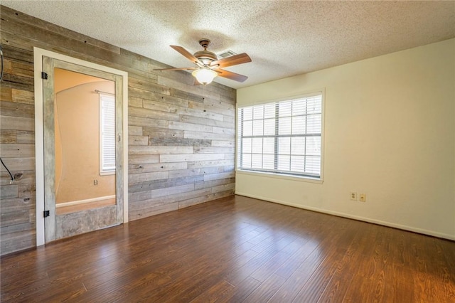 empty room with dark hardwood / wood-style flooring, ceiling fan, and wooden walls