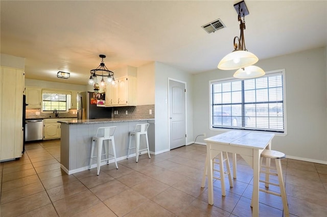 kitchen featuring sink, appliances with stainless steel finishes, tasteful backsplash, kitchen peninsula, and a breakfast bar area