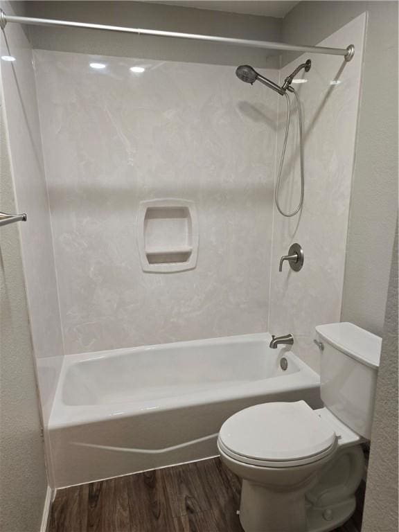 bathroom with wood-type flooring, tub / shower combination, and toilet