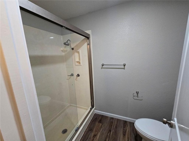 bathroom featuring hardwood / wood-style floors, a shower with door, and toilet