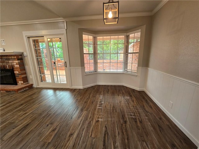 unfurnished dining area featuring crown molding, dark hardwood / wood-style flooring, and a fireplace