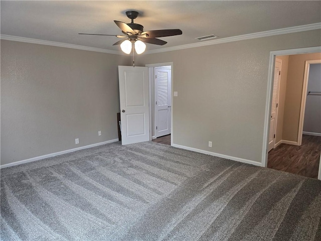 unfurnished bedroom with ceiling fan, dark carpet, ornamental molding, and a closet