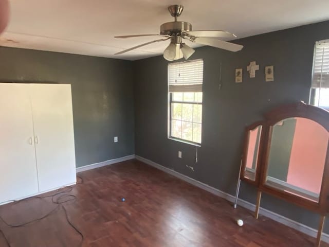 unfurnished bedroom featuring ceiling fan and dark wood-type flooring