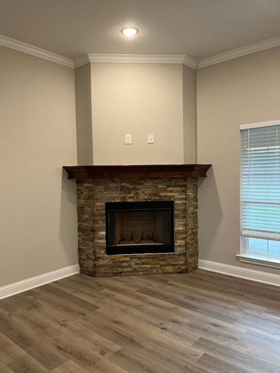 room details with wood-type flooring, a stone fireplace, and ornamental molding