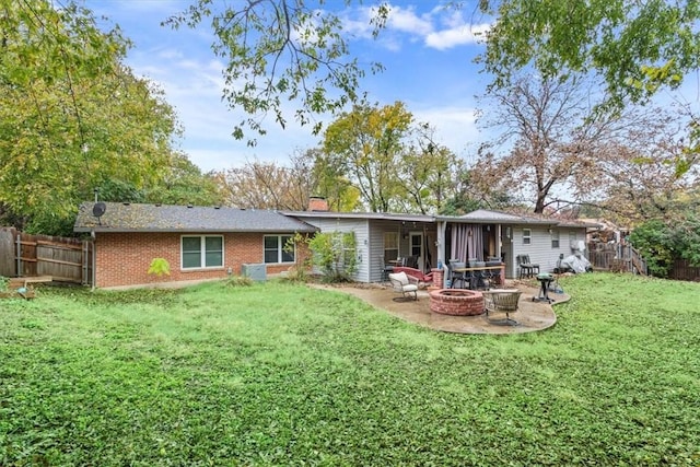 back of property with a yard, an outdoor fire pit, and a patio area