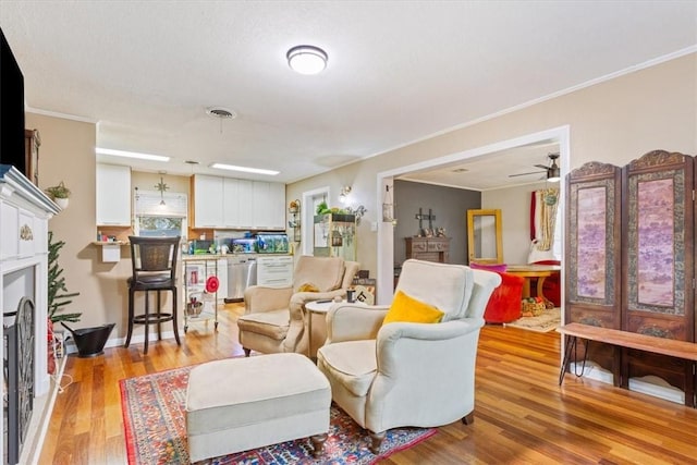 living room featuring light hardwood / wood-style floors, ceiling fan, and ornamental molding