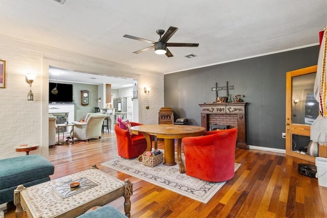 living room featuring ceiling fan, dark hardwood / wood-style flooring, ornamental molding, and a fireplace