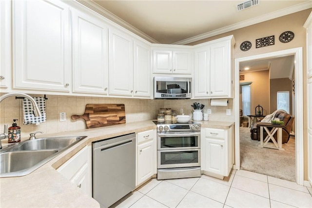 kitchen featuring light carpet, white cabinets, sink, ornamental molding, and stainless steel appliances