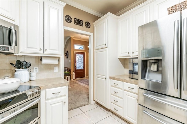 kitchen featuring white cabinetry, crown molding, light tile patterned floors, and stainless steel appliances