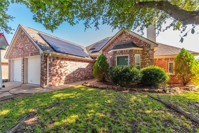 view of front of home featuring a garage, a front yard, and solar panels