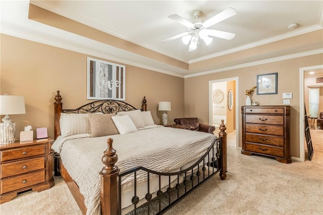 carpeted bedroom featuring ceiling fan, a raised ceiling, ornamental molding, and connected bathroom