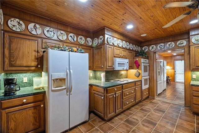 kitchen featuring tasteful backsplash, ceiling fan, dark tile patterned floors, and white appliances