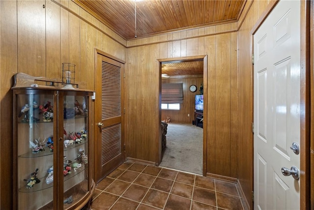 corridor with wooden walls, dark carpet, and wooden ceiling