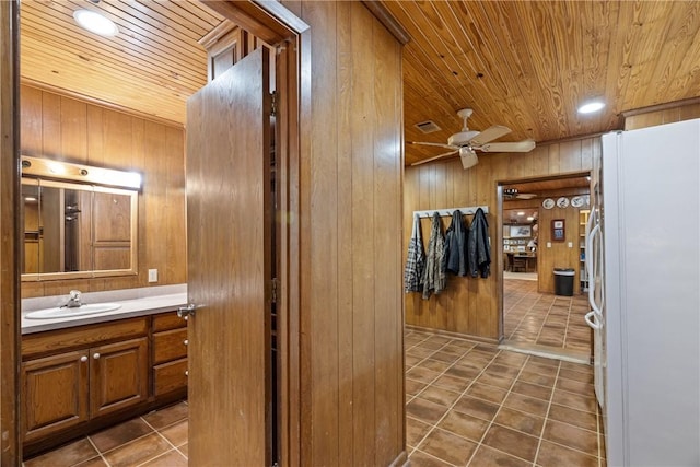 bathroom featuring vanity, ceiling fan, wooden walls, and wood ceiling