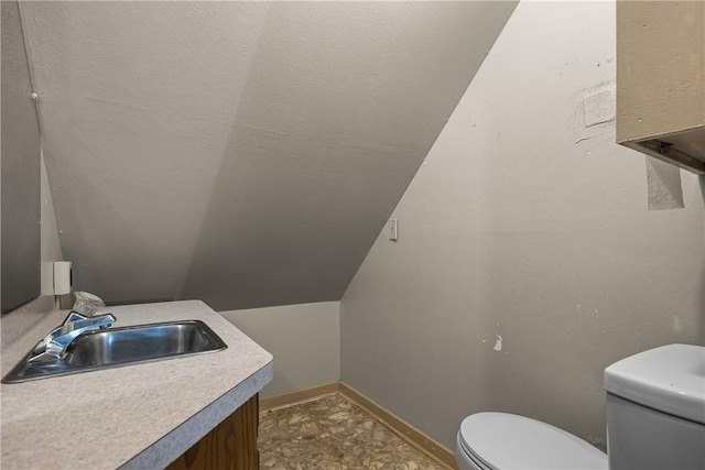 bathroom featuring toilet, vanity, and vaulted ceiling