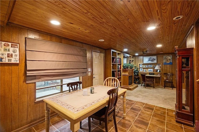 dining room featuring dark colored carpet, wooden walls, and wood ceiling