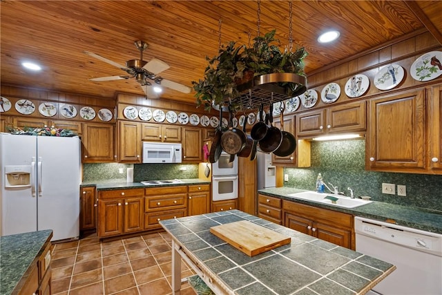 kitchen featuring white appliances, backsplash, tile patterned floors, sink, and a kitchen island