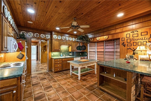 kitchen with white appliances, dark tile patterned floors, wooden walls, ceiling fan, and wooden ceiling