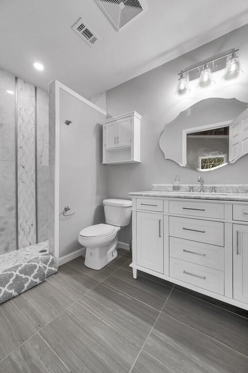 bathroom with a shower, vanity, and toilet