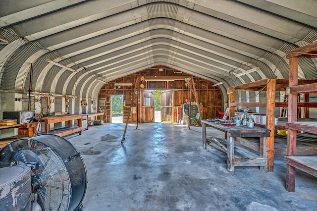 miscellaneous room with a workshop area, wood walls, concrete floors, and vaulted ceiling