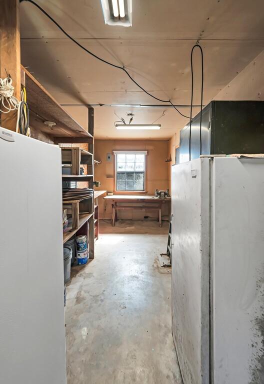 basement with a workshop area and white fridge