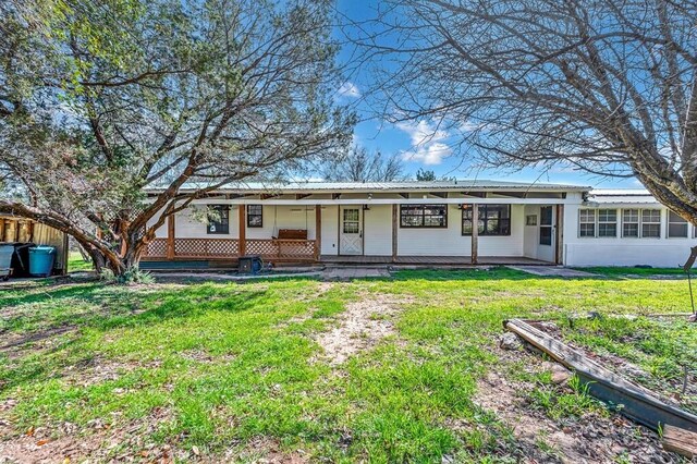 back of property with covered porch and a yard