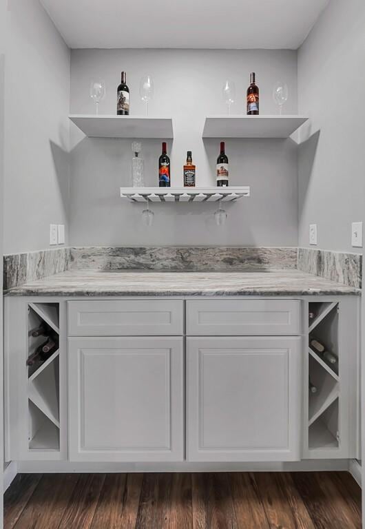 bar with white cabinets and dark wood-type flooring