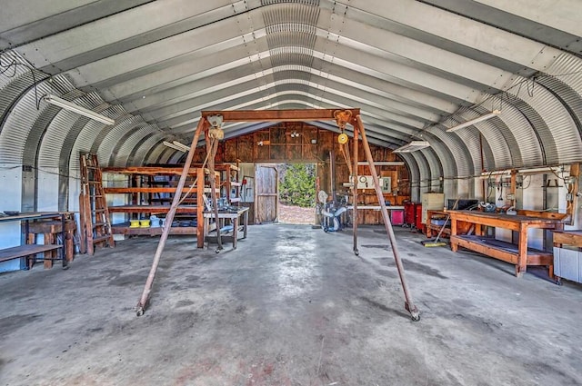 miscellaneous room featuring concrete flooring, lofted ceiling with beams, and a workshop area