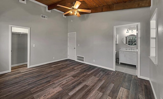 unfurnished bedroom featuring vaulted ceiling with beams, dark hardwood / wood-style flooring, wooden ceiling, and ensuite bathroom