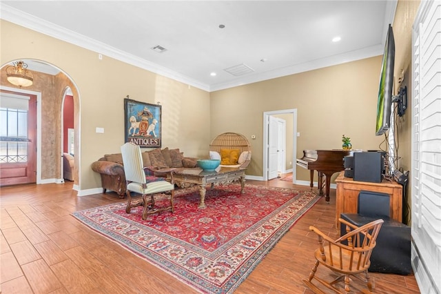 living area featuring visible vents, crown molding, baseboards, wood finished floors, and arched walkways