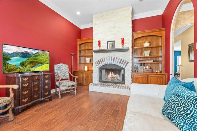 living room featuring a fireplace, wood finished floors, baseboards, and ornamental molding