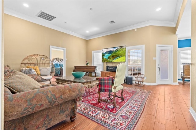 living area with crown molding, wood finished floors, and visible vents