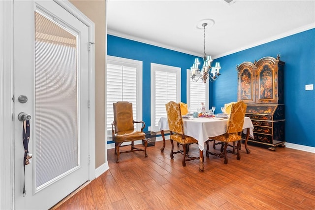 dining room with a notable chandelier, wood finished floors, baseboards, and ornamental molding