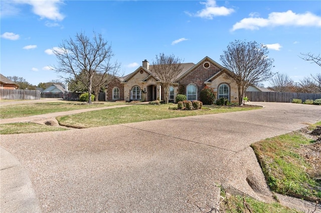 view of front of house with concrete driveway, a chimney, a front lawn, and fence