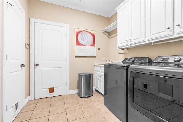 clothes washing area with washer and dryer, cabinet space, crown molding, light tile patterned floors, and baseboards