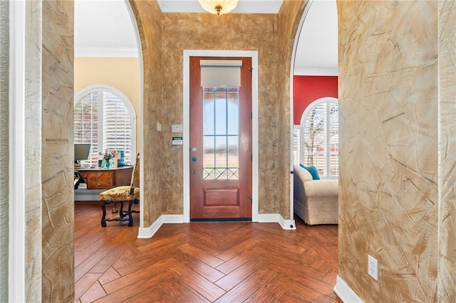 foyer featuring baseboards, arched walkways, a healthy amount of sunlight, and crown molding