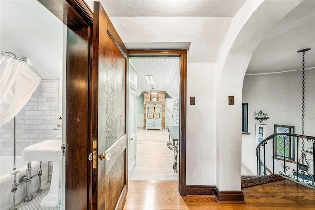 hall with tile walls and light wood-type flooring