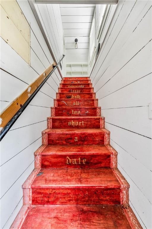 stairway featuring wood walls