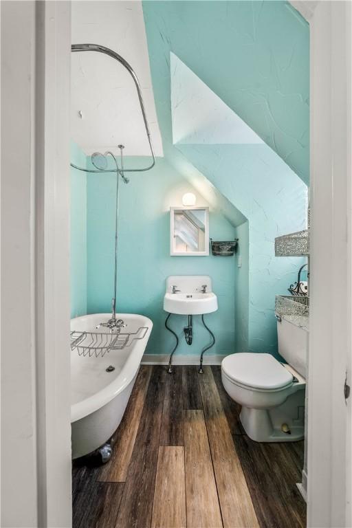 bathroom with a washtub, wood-type flooring, and toilet