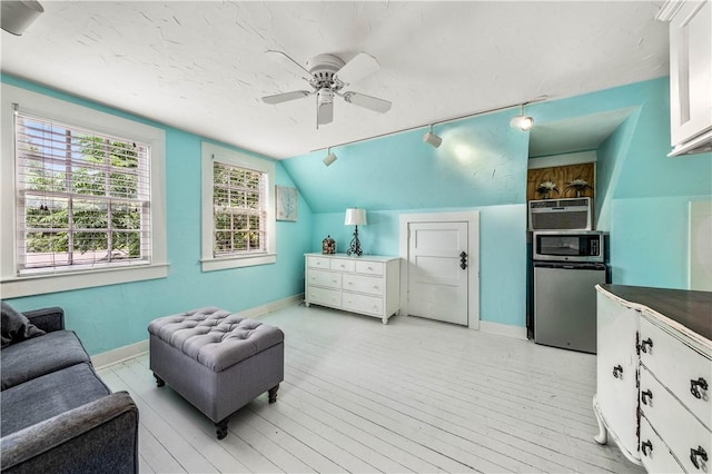 bedroom with ceiling fan, stainless steel fridge, light wood-type flooring, and vaulted ceiling