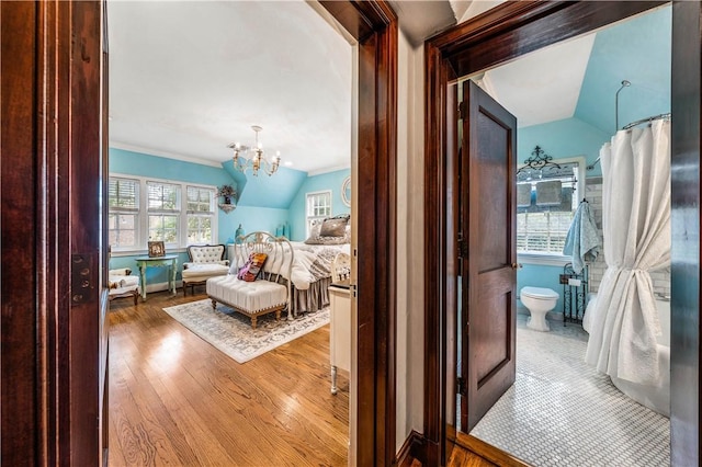 bedroom with ensuite bath, ornamental molding, vaulted ceiling, a notable chandelier, and light hardwood / wood-style floors