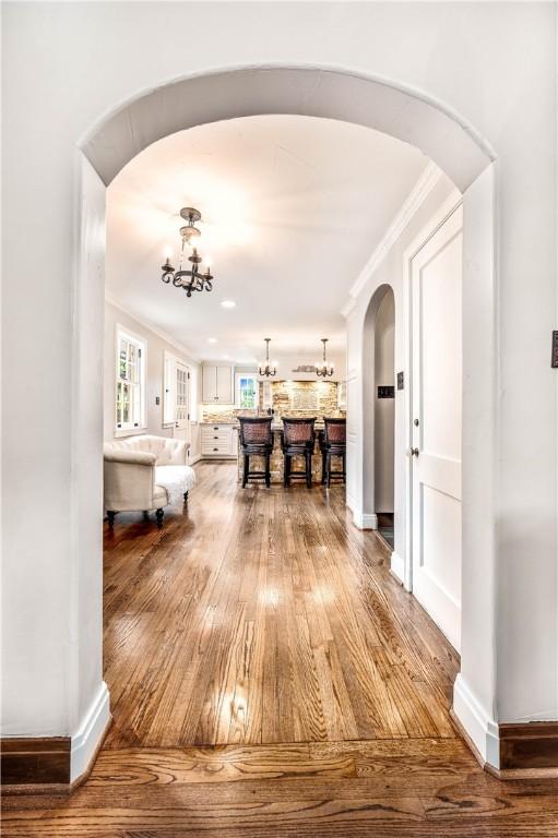 hallway with crown molding, hardwood / wood-style floors, and a chandelier