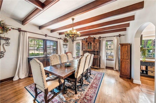 dining room featuring a chandelier, light wood-type flooring, and beamed ceiling